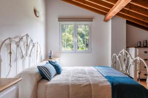 a bedroom with a white bed with blue pillows at Casa do Dízimo in Furnas