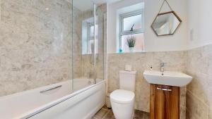a bathroom with a toilet and a sink and a bath tub at Weldon Road - Townhouse Overlooking the Park with Parking in Swanscombe