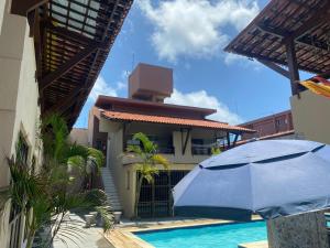 a blue umbrella in front of a house with a swimming pool at Enseadas dos corais in Cabo de Santo Agostinho +1 photo