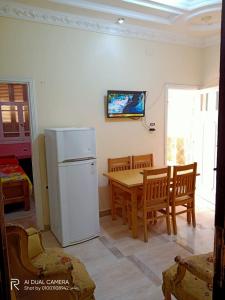 een keuken met een tafel en een witte koelkast bij شقة مفروشة للايجار فى راس البر سادس مطل من البحر in Ras El Bar