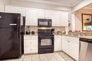 une cuisine avec des armoires blanches et un réfrigérateur noir dans l'établissement Litchfield 1BR Getaway at Seaside Inn, à Pawleys Island