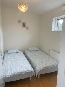 two beds in a room with a window and a chandelier at Villa in Stockholm 