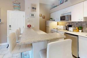 a kitchen with white cabinets and a counter with white chairs at Condo 713 at North Creek Resort in Blue Mountains