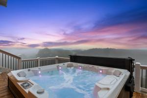 a jacuzzi tub on a deck with a sunset at Perch in the Clouds Hot Tub Stunning Views in Ellijay