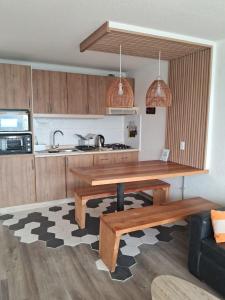 a kitchen with a wooden table and a counter top at Departamento frente al mar, con piscinas y vista panorámica in Puchuncaví