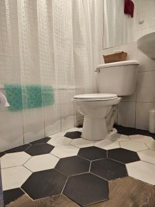 a bathroom with a toilet and a black and white tile floor at Departamento frente al mar, con piscinas y vista panorámica in Puchuncaví