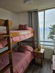 a bedroom with two bunk beds and a window at Departamento frente al mar, con piscinas y vista panorámica in Puchuncaví