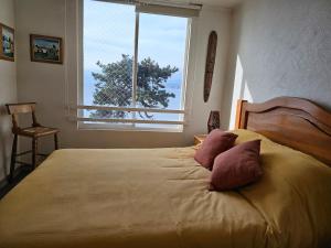 a bedroom with a large bed with a large window at Departamento frente al mar, con piscinas y vista panorámica in Puchuncaví +46 photos