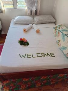 a bed with a welcome sign and flowers on it at PELLY Homestay Explorer in Vunivuthea