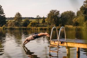 a man is in the water near a dock at NaturResort Steinwald in Krummennaab