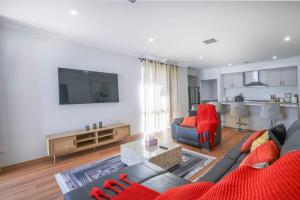 a living room with a couch and a red chair at Urban Virgo Escape in Caversham
