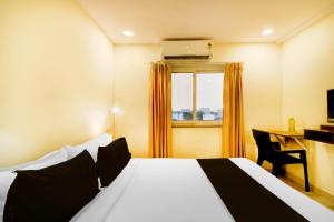 a bedroom with a bed and a desk and a window at Super Townhouse De Alphabet Hotel - Gandimaissamma in Hyderabad