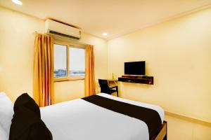 a hotel room with a bed and a television at Super Townhouse De Alphabet Hotel - Gandimaissamma in Hyderabad