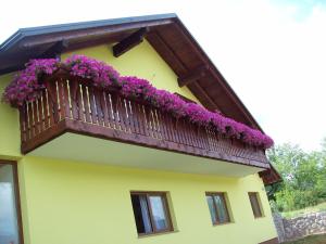 a yellow building with a balcony with purple flowers at House Mara in Korenica