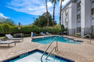 a swimming pool with chairs and a building at Spark by Hilton Phoenix-Glendale-Peoria in Glendale