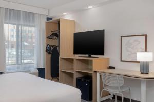 a bedroom with a bed and a desk with a television at Spark by Hilton Bentonville in Bentonville