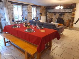 a table with a red table cloth on it in a living room at LA LONGÈRE - Chambre Aubrac 