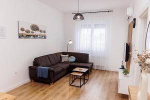 a living room with a brown couch and a table at Apartman Bonus in Palić