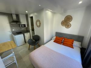 una camera da letto con letto con cuscini arancioni e una cucina di Suites nuevas con baño privado frente al metro st MWC Barcelona-FIRA a Hospitalet de Llobregat