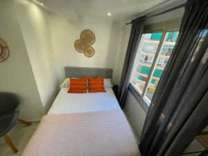 un lettino con cuscini arancioni in una stanza con una finestra di Suites nuevas con baño privado frente al metro st MWC Barcelona-FIRA a Hospitalet de Llobregat