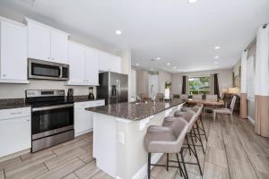 eine Küche mit weißen Schränken und eine Bar mit Barhockern in der Unterkunft Spacious Home With Private Pool, Themed And Game Room Near Disney With Waterpark & Resort Access - 341Pn in Kissimmee