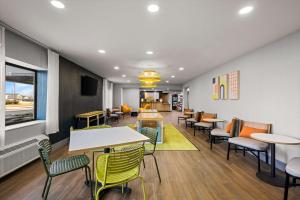a waiting room with tables and chairs in a restaurant at Spark By Hilton Fort Wayne in Fort Wayne