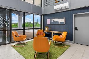 a waiting room with orange chairs and a desk at Spark by Hilton Lexington Hamburg in Lexington