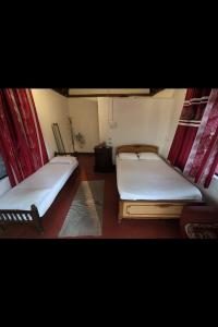 two beds in a room with red curtains at Tribal land homestay in Kushālnagar