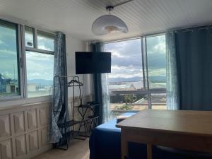 a bedroom with a bed and a table and windows at PENTHOUSE SEASIDE 10 MIN port, croisière et aéroport in Pointe-à-Pitre