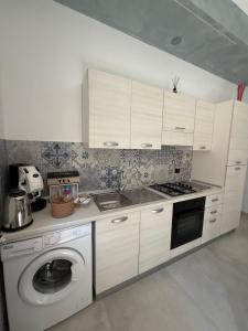 a kitchen with white cabinets and a washing machine at Vico Terzo Guest House in Deliceto