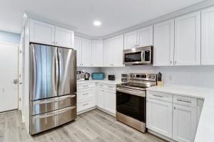 une cuisine avec des armoires blanches et un réfrigérateur en acier inoxydable dans l'établissement Stunning 2 Bedroom Villa Steps to the Beach, à Île de Hilton-Head