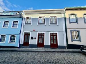 a group of buildings with red doors on a street at Vera Cruz Guesthouse in Angra do Heroísmo