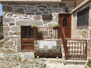 a stone building with a balcony with plants on it at Cantinho das Tecedeiras in Mondim de Basto