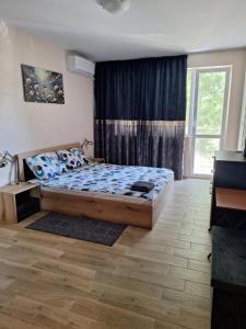 a bedroom with a bed and a large window at Бобс апартменти in Kiten