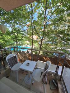 a balcony with a table and chairs and trees at Бобс апартменти in Kiten