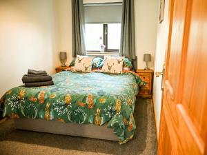 a bedroom with a bed with a green comforter and a window at 2 Bed in Llandrindod Wells 88203 in Llandegley