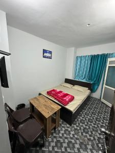 a small room with a bed and a table and chairs at Pearl Homestay Mussoorie in Mussoorie