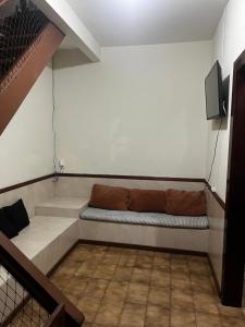a couch sitting in a room with a tv at Rico Hostel in Cabo Frio