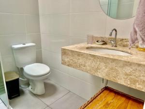 a bathroom with a toilet and a sink and a mirror at Casa aconchegante e com quintal privativo in Matinhos +30 photos
