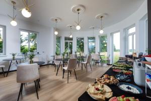 a dining room with tables and chairs and windows at Villa Scolia in Niechorze
