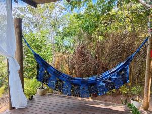 a blue hammock on a deck with trees at Casa Contêiner imersão com Natureza Floresta Sapiranga-5km praia do forte in Mata de Sao Joao