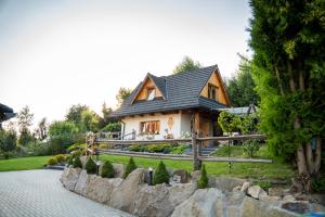 a house with a black roof and a stone walkway at Domek 'Słoneczna 2' z RUSKĄ BANIĄ in Kluszkowce