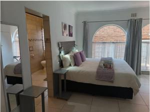 Un dormitorio con una cama grande y una ventana grande. en Oppiplot Guest House, en Kempton Park