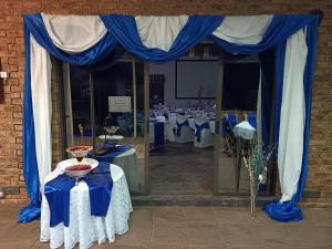 Un montaje para un banquete con cortinas y mesas azules. en Oppiplot Guest House, en Kempton Park