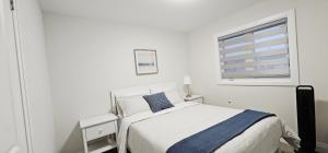 a white bedroom with a bed and a window at Muskoka Luxury Getaway in Gravenhurst