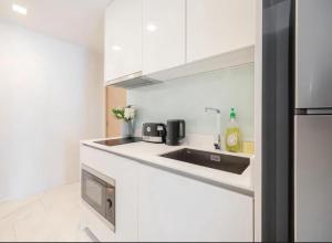 a kitchen with white cabinets and a sink at Hyde Sukhumvit 11 Bankok in Bangkok +13 photos
