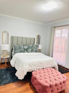 a bedroom with a large bed with a pink ottoman at Fully Furnished 3 bedroom apartment rental in Roodepoort