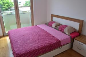- une chambre avec un lit rose et une fenêtre dans l'établissement Masha Apartment, à Budva