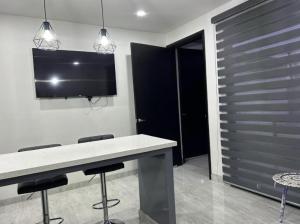 una cucina con tavolo con sgabelli e una TV a parete di Suite Marvento, Departamento 4 a Ensenada