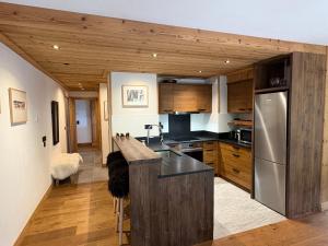a kitchen with wooden cabinets and a stainless steel refrigerator at Appartement 4 à la Ferme des Lanches au Praz in Courchevel